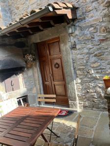 a wooden table in front of a stone building with a door at B&B QUIConti in Agnino