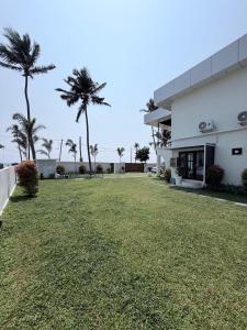 a large yard in front of a building with palm trees at LAGUNA BLU beach villa in Irimbranallūr