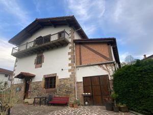 a large white building with a balcony on top of it at Casa Rural Donamariako Benta in Donamaría