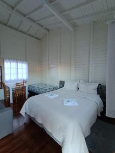 a bedroom with a large white bed and a table at Pousada Landhaus in Urubici