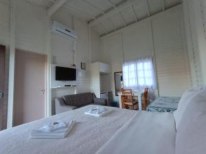 a bedroom with a white bed and a living room at Pousada Landhaus in Urubici