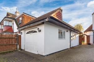 a white garage with a brown roof at Private Annex with Gated Driveway near Grove Park Station in Hither Green