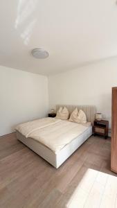 a white bedroom with a bed and a wooden floor at HOUSE CAMELIA - Stilvolles, großzügiges 2-Zimmer-Apartment in Irrel