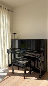 a black piano with a bench in a room at HOUSE CAMELIA - Stilvolles, großzügiges 2-Zimmer-Apartment in Irrel
