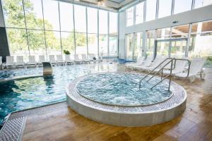 a hot tub in a large room with windows at Aquasolis Spa Hotel in Poľný Kesov