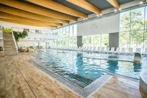 a large swimming pool with chairs in a building at Aquasolis Spa Hotel in Poľný Kesov