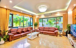 a living room with leather couches and a flat screen tv at FLC Grand Villa BT31-23 in Sầm Sơn