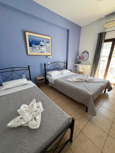 two beds in a bedroom with blue walls at Stella Nomikou Apartments in Firostefani +156 photos
