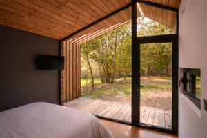 a bedroom with a large glass door leading to a deck at Cabañas en Ribeira Sacra, Borbela de Luz in Villar de Ordelles