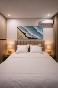 a bedroom with a large white bed with two lamps at Dakar Roi - Point E - Modern Studio - Central Location in Dakar