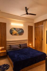 a bedroom with a blue bed and a ceiling fan at The Happy Nook Stays in Winsten Park Knowledge Park V in Noida