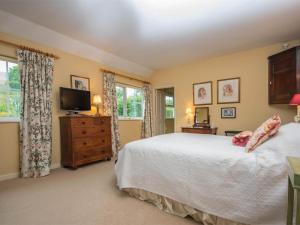 a bedroom with a bed and a tv and windows at 4 Bed in Bridport oc-dc195 in Loders