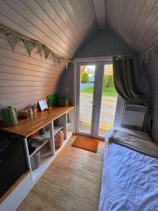 a room with a bed and a desk and a window at Little Green Glamping Pod in Narberth