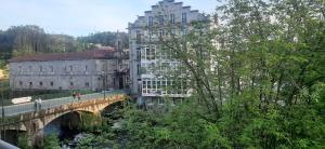 a bridge over a river with a building and a building with a bridge at Caldasia in Caldas de Reis