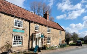 an old brick building with a sign in front of it at Coxwold Tearoom in Coxwold
