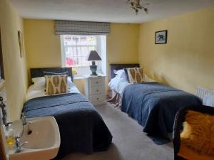 a bedroom with two beds and a sink in it at Coxwold Tearoom in Coxwold