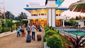 a group of people walking in front of a house with luggage at achi gest house in Mulliyavalai