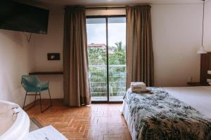a bedroom with a bed and a bathroom with a window at Hotel Macaw Cúcuta in Cúcuta