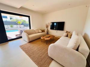 a living room with a couch and a tv at Vila Esnella - Private Pool & Panoramic Sea view in Primošten