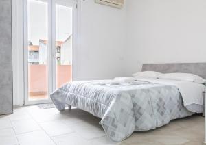 a white bedroom with a bed and a large window at Ischera Apartments in Guspini