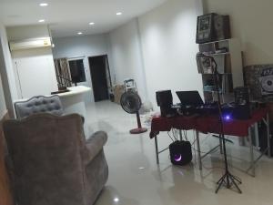 a living room with a chair and a desk with a fan at Sunset Groove Cafe in Nong Prue