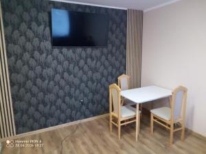 a table and two chairs and a television on a wall at Krakowski in Boguszów-Gorce