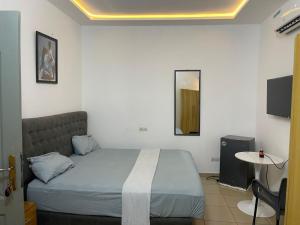 a bedroom with a bed and a table and a tv at Guest House HEBERTOGO in Lomé