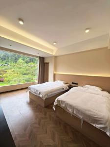 a bedroom with two beds and a large window at NAIYI Forest Park Resort in Zhangjiajie