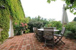 a patio with a table and chairs and an umbrella at La Chaume en Loire in Devay