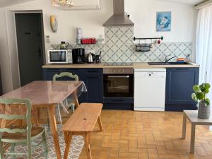 a kitchen with blue cabinets and a wooden table at Carabas84 in Carpentras