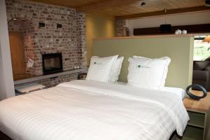 a bedroom with a large white bed with a fireplace at Vakantiehuis 1 - Ter Douve in Heuvelland