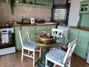 a kitchen with green cabinets and a glass table and chairs at Gozo Duplex Studio overlooking historic Piazza in Victoria