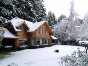 a wooden house with snow on the ground at Cabañas Rincon del Lago in Villa La Angostura