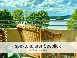 a wicker chair on a balcony with a view of the water at Heimathafen Dieksee - mit direktem Seeblick & Balkon am Dieksee in Malente