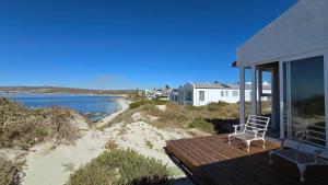 a chair sitting on a deck next to the beach at Ashore - Beachfront Paradise in St. Helena Bay