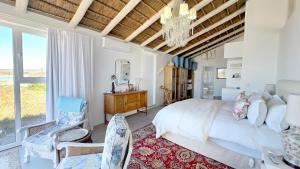 a bedroom with a bed and a table and chairs at Ashore - Beachfront Paradise in St. Helena Bay