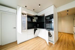 a kitchen with white cabinets and a washer and dryer at Еlite central stay apartment in Pleven
