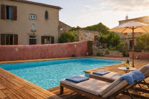a pool with chairs and an umbrella on a wooden deck at Domaine du Prieuré avec Piscine Ancien Couvent & Presbytère in Carcassonne