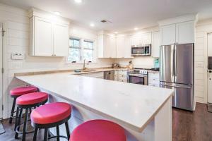 a kitchen with white cabinets and pink bar stools at Fiddlers Hideaway in Kiawah Island