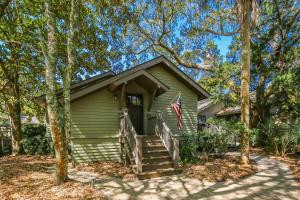 a green house with a porch with a flag at Fiddlers Hideaway in Kiawah Island