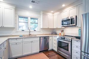 a kitchen with white cabinets and stainless steel appliances at Fiddlers Hideaway in Kiawah Island +42 photos