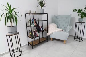 a black book shelf next to a chair and a plant at Willa Nowa 33 in Wisła