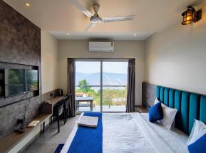 ein Schlafzimmer mit Bett, Fernseher und Fenster in der Unterkunft Holiday Plus in Panchgani
