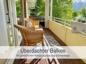 a porch with wicker chairs and a table on a balcony at Heimathafen Dieksee - mit direktem Seeblick & Balkon am Dieksee in Malente