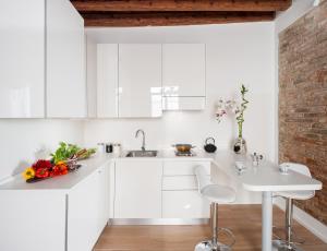 a kitchen with white cabinets and a sink and a table at Ca del Mar Venice Luxury Apartments in Venice