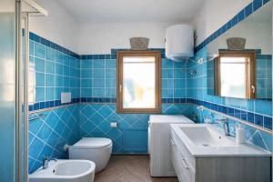 a blue tiled bathroom with a toilet and a sink at Lucia House in Santa Lucia