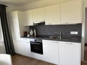 a kitchen with white cabinets and a sink at Ferienwohnung Amseltraum in Seeboden