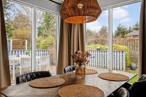 a dining room with a table with chairs and large windows at S745-Stroby-Garderhojen-35 in Strøby
