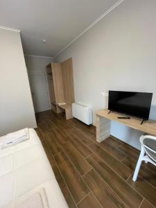 a living room with a flat screen tv and a desk at Clean City Agrotourism in Durrës