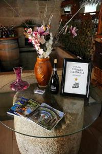 a glass table with a bottle of wine and flowers at Hotel Rural O Salazón in Cambados